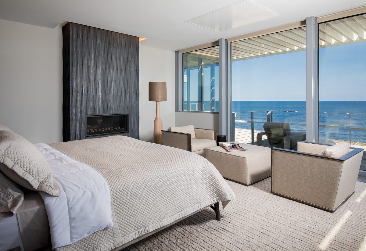 A bed in a room with a view of the ocean.