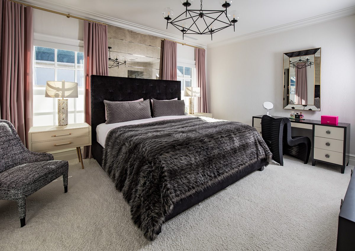 A bedroom with a bed, dresser and mirror.