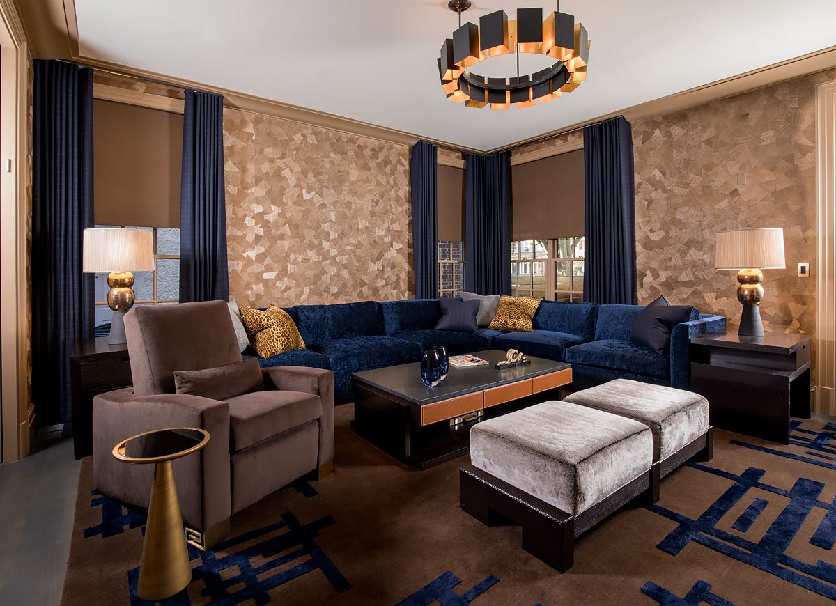 A living room with blue couches and a chandelier.