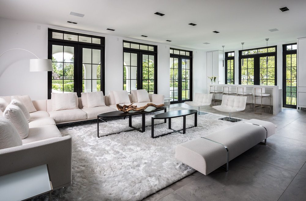 A living room with large windows and white furniture.