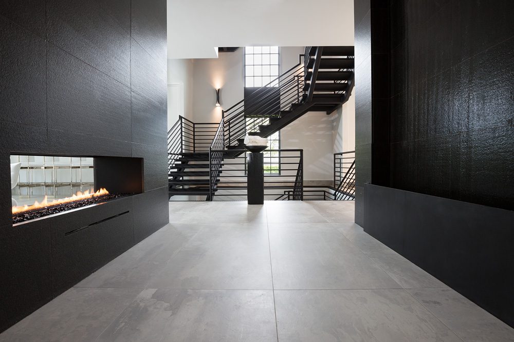 A modern hallway with a fireplace and stairs.