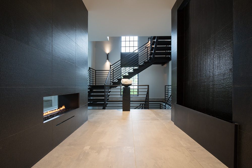 A hallway with black walls and stairs leading to a fireplace.