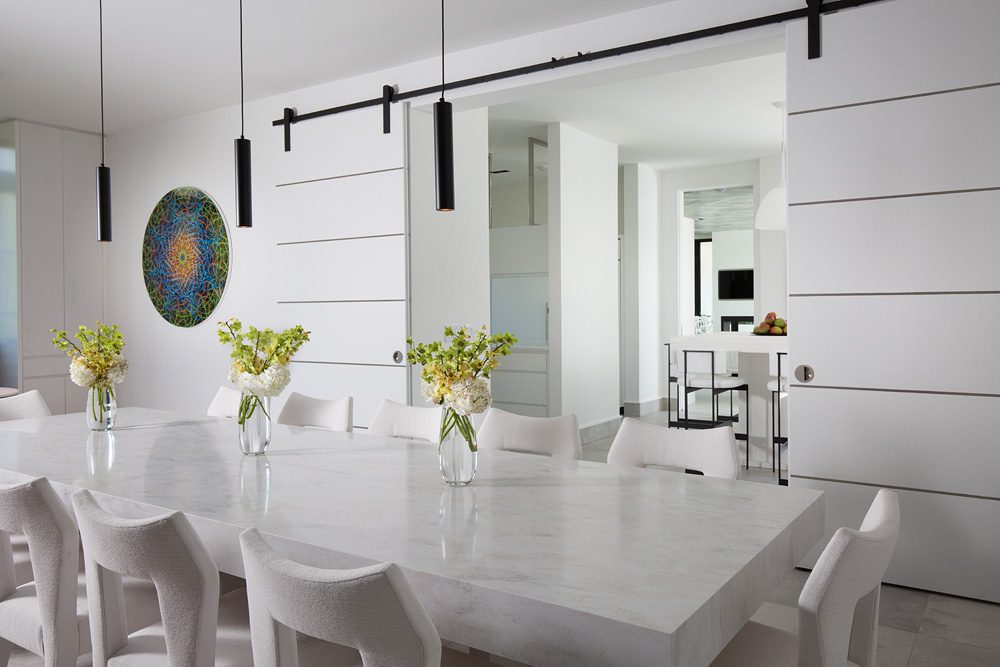 A dining room with white chairs and a white table.