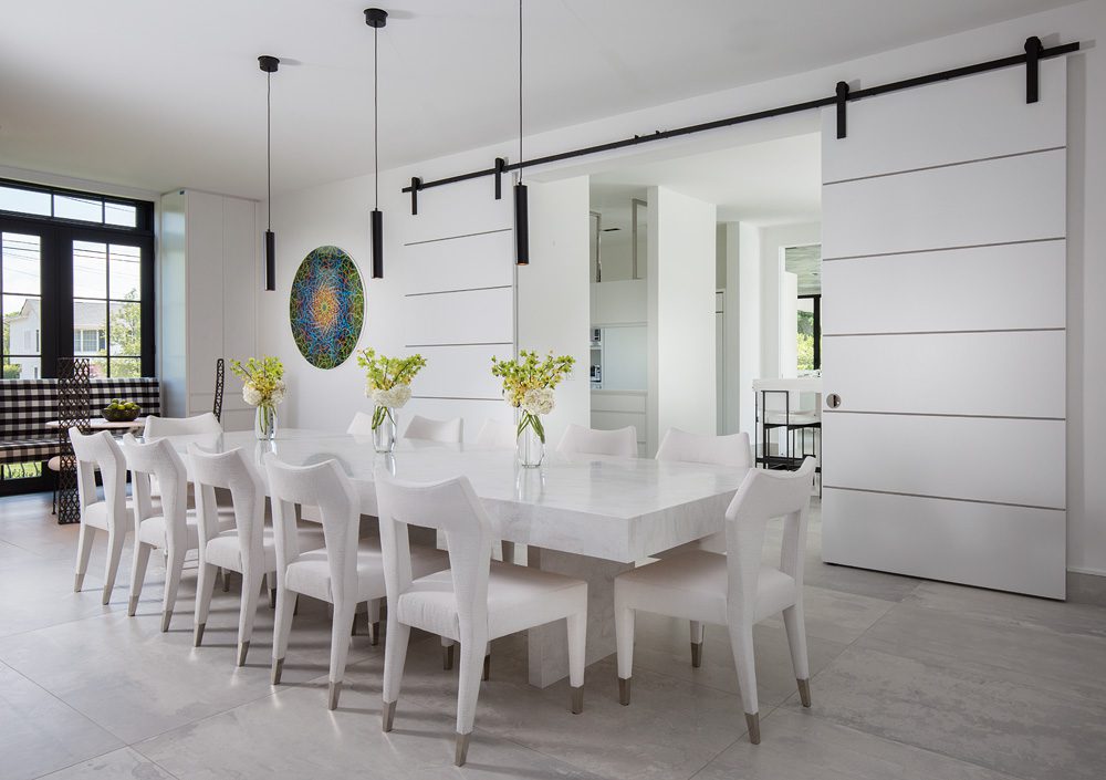 A white dining room with a white table and chairs.