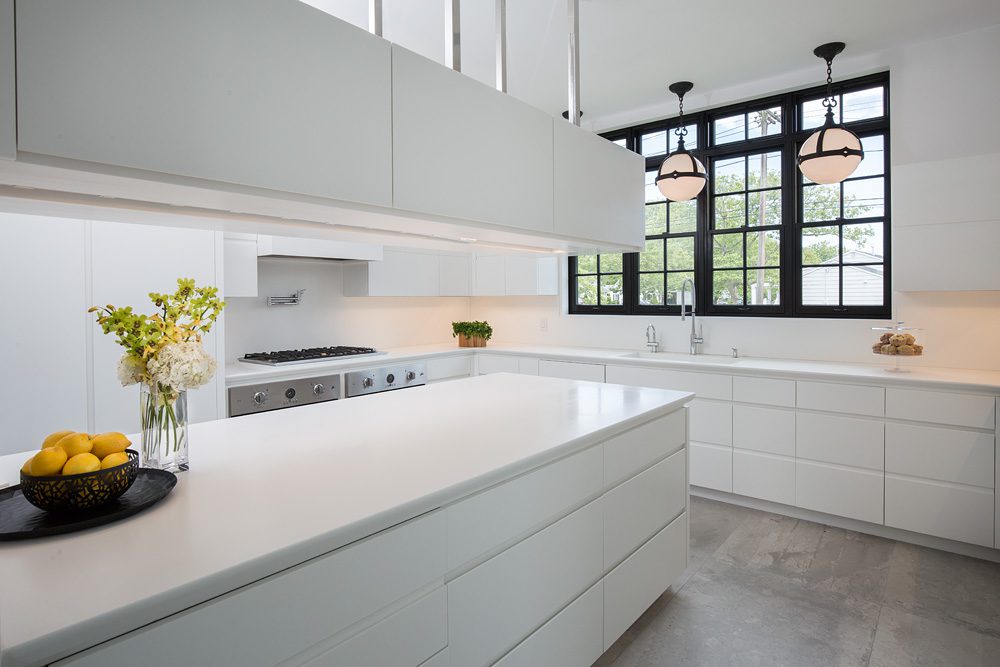 A modern kitchen with white cabinets and a window.