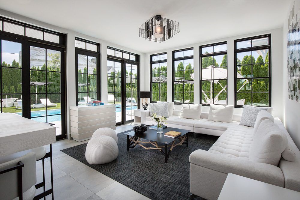 A living room with large windows and white furniture.