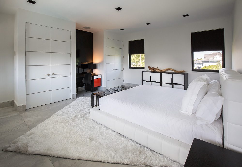 A bedroom with a white bed and black furniture.