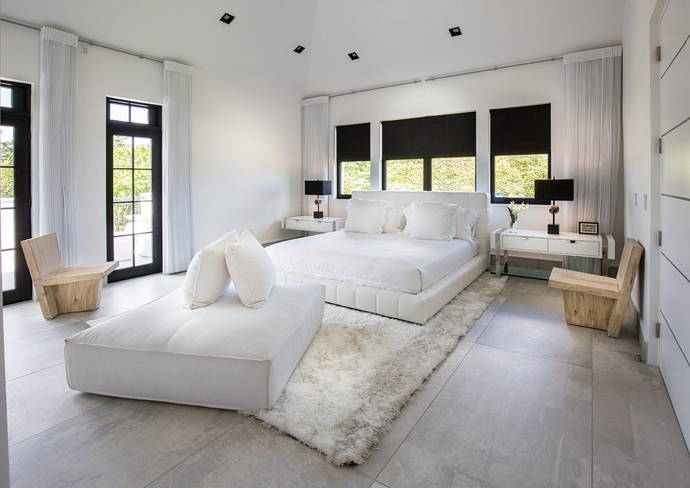 A bedroom with a white bed and white furniture.