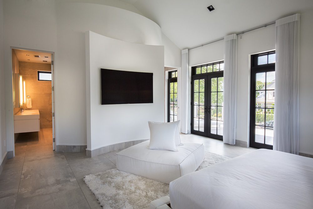 A white bedroom with a tv on the wall.