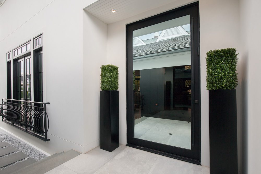 A black door with a planter in front of it.