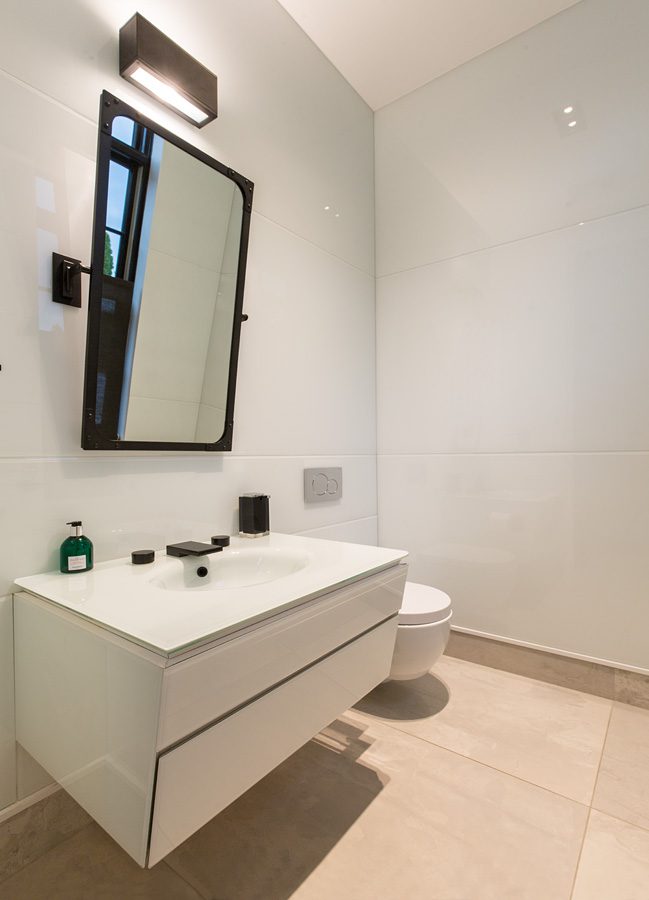 A white bathroom with a sink and mirror.